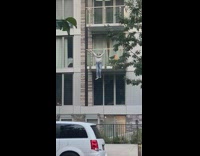 Mannequin Hangs Beside Building Terrace Across Street