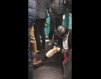 Guy gets on the floor, pulls up pants sleeve and rubs knee on crowded train