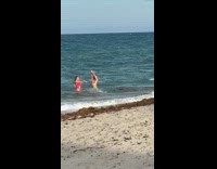 Two girls splash beach water guy seaweed