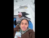 Kid serious face snow tubing with mom