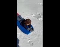 Girl lay on boogie board slide on snow