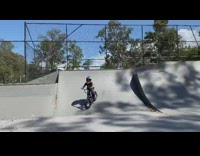 Little boy rides bicycle up ramp skatepark