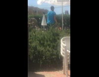Man behind umbrella dances next to swimming pool