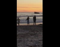 Girls hold sparklers at beach during sunset