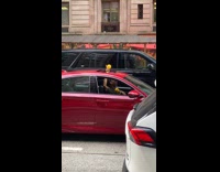 Guy shakes maracas in red car open sunroof 