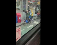 Guy riding bicycle has dog in backpack 