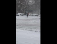 Person walking on snow covered sidewalk with skis