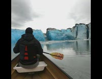 Two guys ride boat towards blue glacier