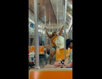 Collab WINY - Woman orange top dances while holds rails inside subway train