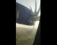 Person looks out plane window during landing 