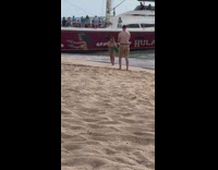 Woman in bikini with grass skirt poses at the beach