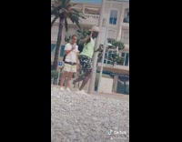 Neon green shirt guy dances sand girl 