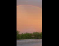 Rainbow arc over buildings orange sunset sky