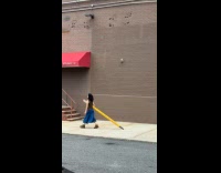 Woman dragging massive pencil on sidewalk