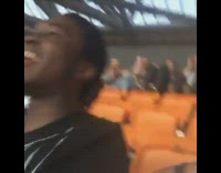 Two guys on one side of concert stadium flash their lights, people from across the stadium copy them