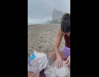 Group of friends trying to picnic at beach in rain 