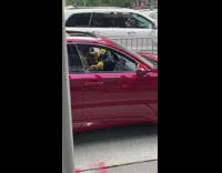 Guy shakes yellow maracas in red car 