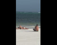 Blonde woman on beach man in speedo laying