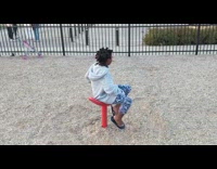 girl on red spinning chair at park