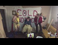 2 guys make noises in front of hot dog banner 