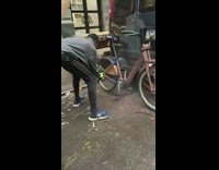 Guy spray painting a bicycle on the street behind van