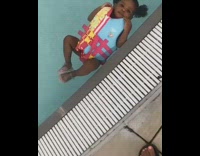 Baby girl floats in swimming with with life vest unbothered
