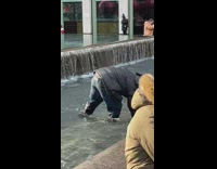 Man picks up coins at the fountain 
