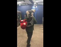 Man walks through subway station turnstiles with dog in jacket standing on shoulders