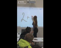 Girl writes equation on board classmates cheer 