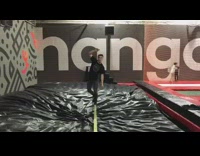 Guy slacklines in a gymnasium falls onto gym mat