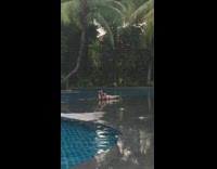 Woman in bikini lie down with a selfie stick