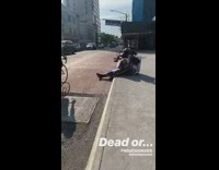 Homeless person sleeps on sidewalk with purple yellow blanket covering body, dead or
