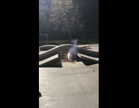 Three guys jump over firework on skateboards 