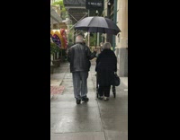 Elderly Couple Walks Down Street on Mothers Day 