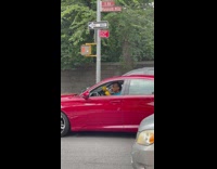 Man in red car playing yellow maracas 