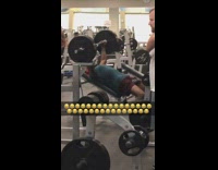 Man blue shirt uses bench press and doesnt drop arms down all the way at gym