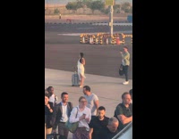 Collab IITW - Woman in white dress with a luggage at the airport runway