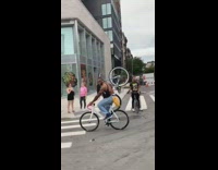 Guy with fanny pack rides white pink bike and holds another bicycle on his shoulders