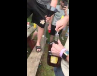 Guy drinks 2 gallon bottle of Crown Royal liquor out of a beer bong as crowd watches