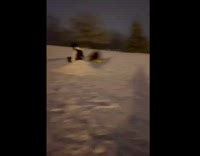 Guy rides green sled over snow pile 