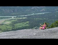 Woman sports bra sit pose on rock mountain