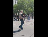 Guy on sidewalk eats cheeseballs using giant knife in hand