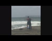 Shirtless guy black shorts exercises beach cliff
