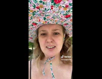 Woman talking about wearing hat in park 