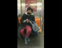 Woman wears visor sunglasses with beads and uses her phone on the subway