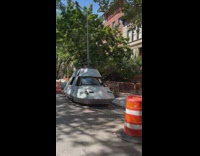 Boat shaped car parked on street by sidewalk 
