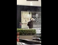 Guy outside on sidewalk waves machete around 