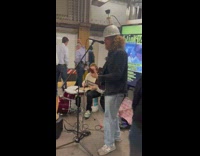 Guitarist performs with cap and bottle on head 