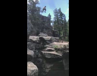Guy in green swimming trunks jumps off rocky cliff and lands in underwater cave