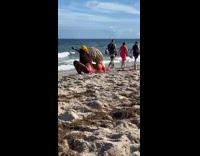 Two girls matching red skirts dance beach 